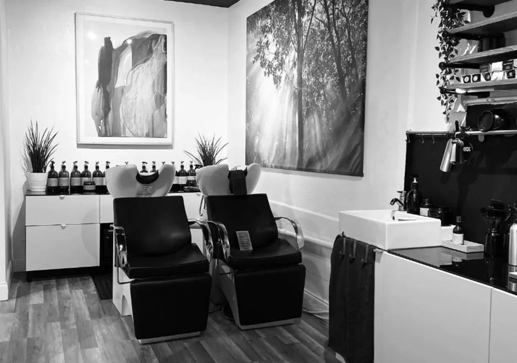 Two salon shampoo chairs in a haircut room with wall art and a sink station. - Ka'ton Salon, Fort Lauderdale FL